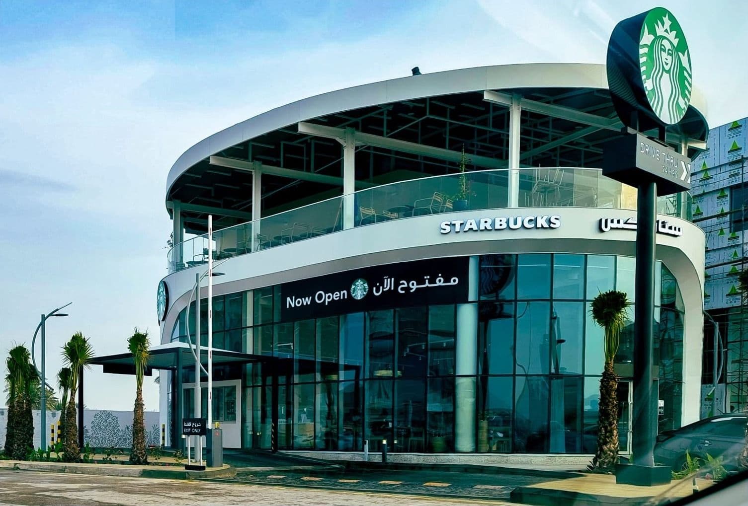Two-storey Starbucks building with a curved glazed facade and green Starbucks sign