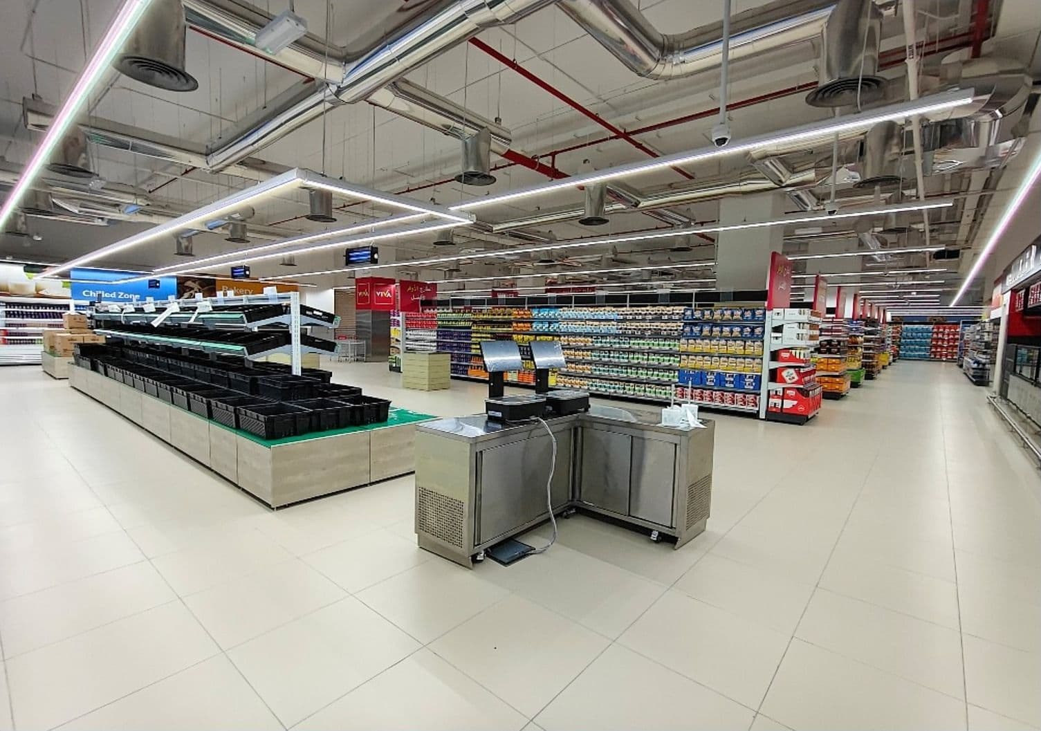 Fresh produce area with display tables and a weighing counter in a hypermarket